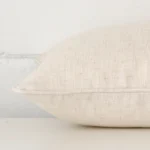 Rectangle cream cushion laid flat. This view shows the linen fabric from side on.