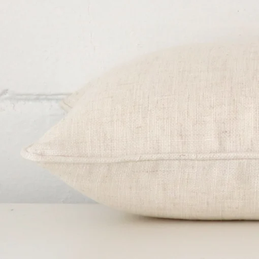 Rectangle cream cushion laid flat. This view shows the linen fabric from side on.