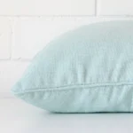 A sideways perspective of this linen cushion. The positioning shows the border of the square shape and the mint colour.