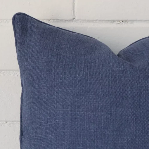 Corner section image showing features of square royal blue cushion that has linen fabric.