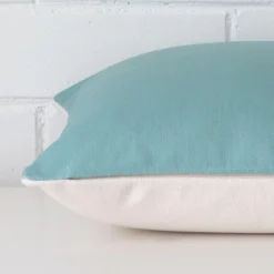 A side view of teal cushion that has linen fabric and a square size.