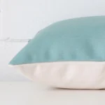 Side perspective showing seam of rectangle teal cushion cover that has a linen fabric.