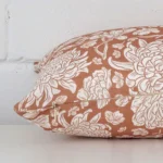 Side angle shot of linen rectangle cushion cover. The terracotta hue and floral style are shown along its seams.