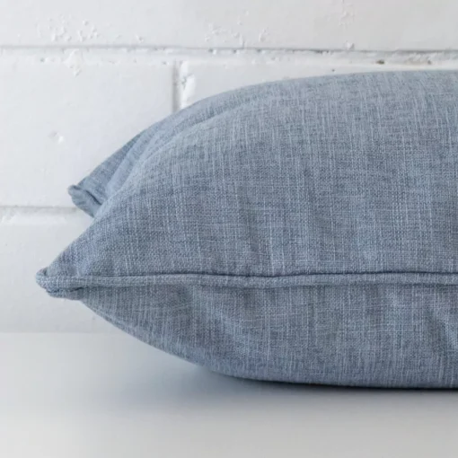 A side view of blue cushion that has linen fabric and a square size.