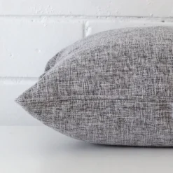 Side perspective showing seam of square grey cushion cover that is made from a linen fabric.