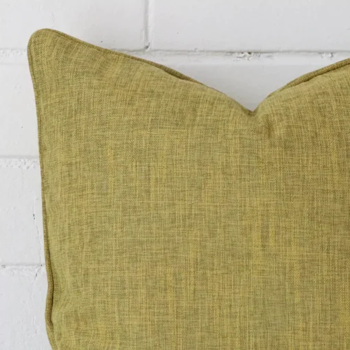 Cropped shot of top left corner of this olive cushion cover. This viewpoint shows the linen fabric and square shape with more precision.