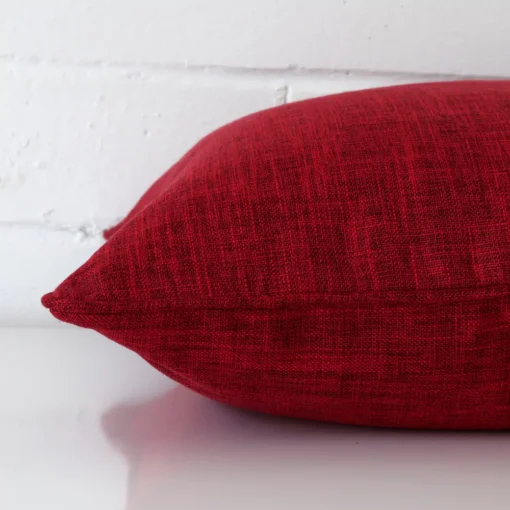 Linen red maroon cushion laying on its side. It has a square size.