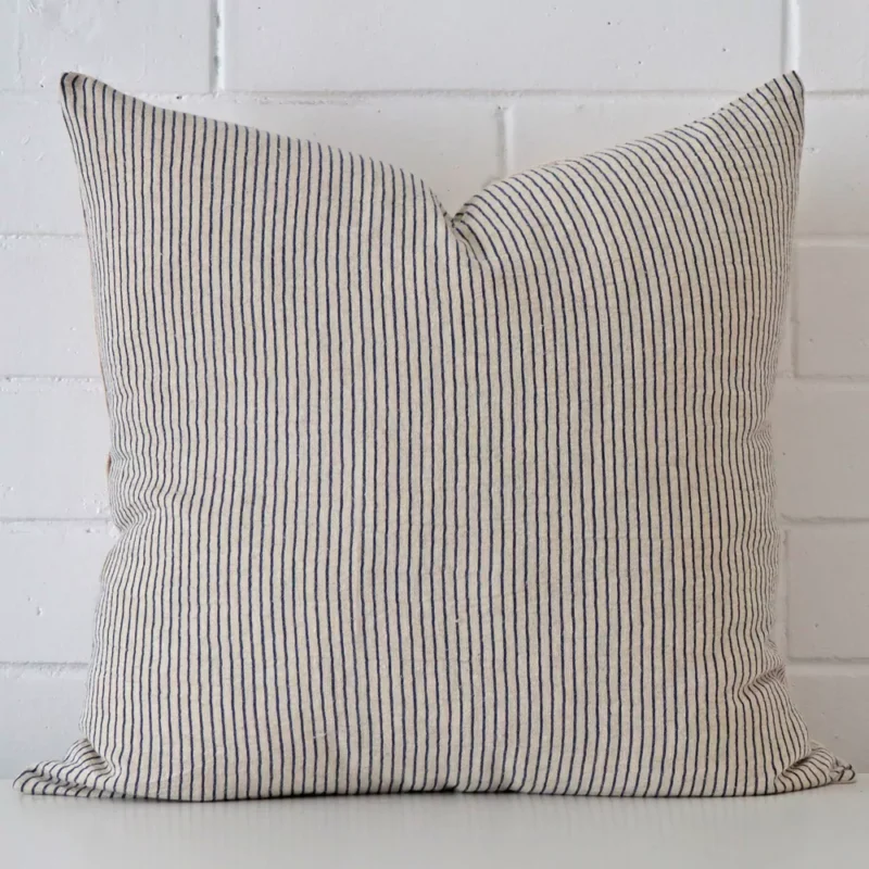 arlo-striped-designer-cushion-cover-art107-55 White wall with a striped style cushion laying against it. It has a distinctive designer fabric and has a square shape.