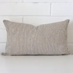 Bold rectangle cushion positioned in front of white brickwork. Its striped style pops on the designer fabric.
