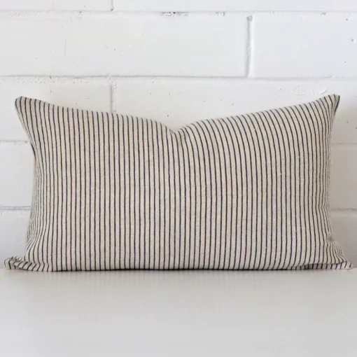 Bold rectangle cushion positioned in front of white brickwork. Its striped style pops on the designer fabric.