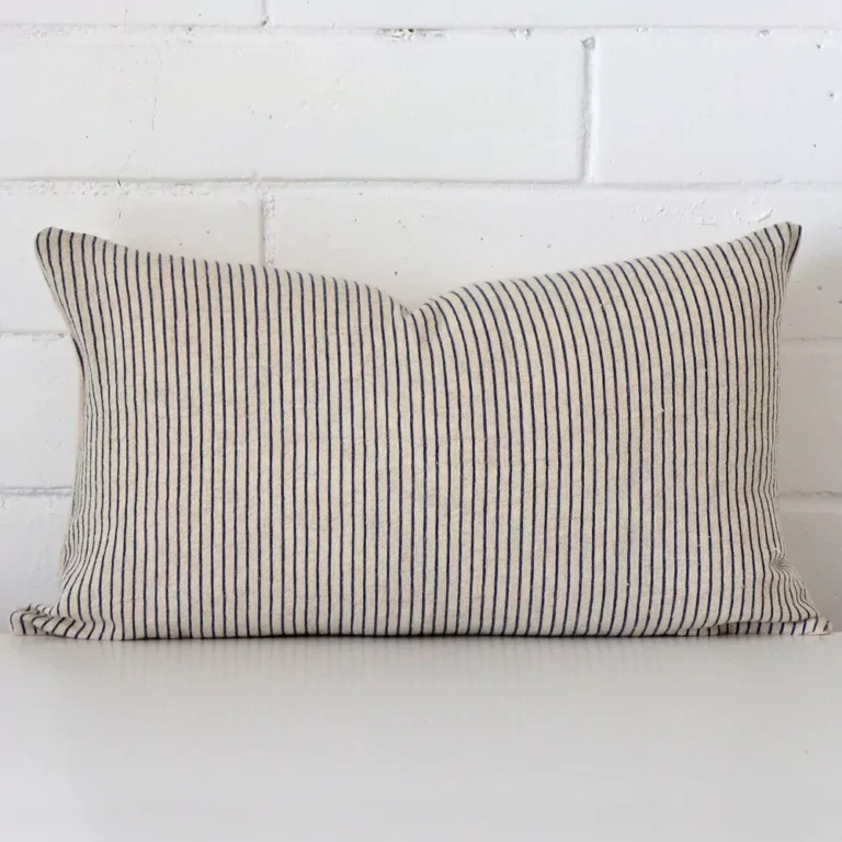Bold rectangle cushion positioned in front of white brickwork. Its striped style pops on the designer fabric.