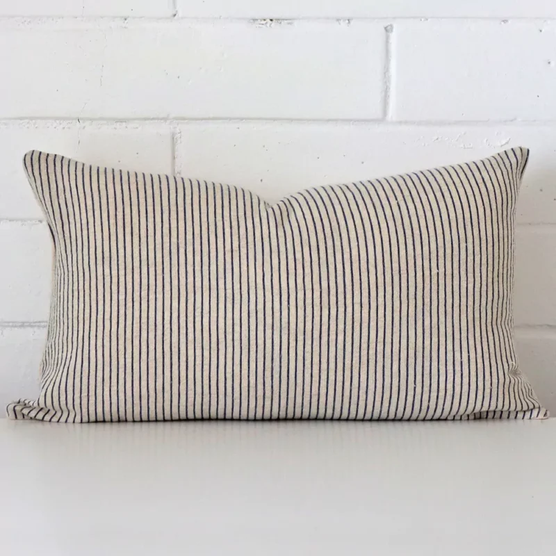Bold rectangle cushion positioned in front of white brickwork. Its striped style pops on the designer fabric.