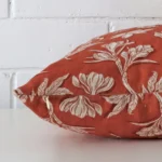 Square floral cushion cover in rust colour sitting flat. The sideways viewpoint shows the seams of the linen material.