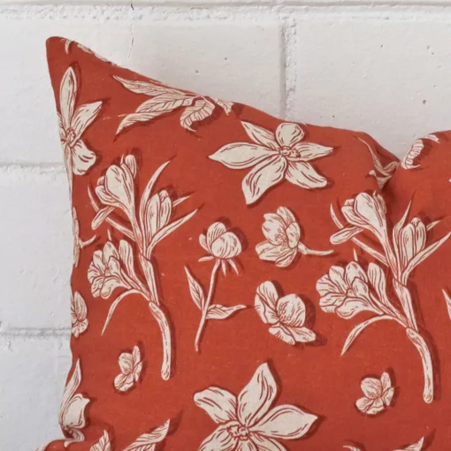 Very close photo of rust floral cushion. The shot shows the linen material and rectangle dimensions with more clarity.