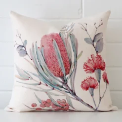 Linen cushion cover features prominently against a white wall. It is a square design and has a floral decorative finish.