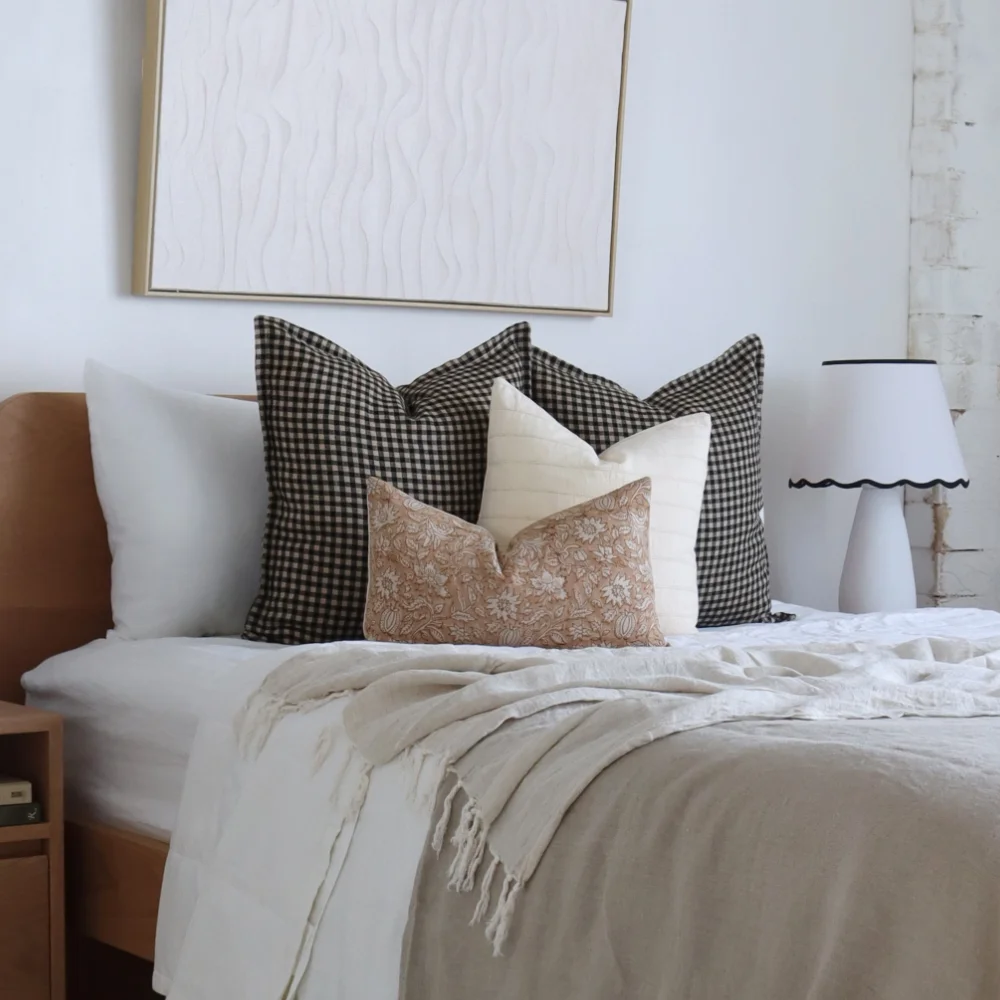 Four bed cushions styled in a bright bedroom.