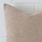 A macro image of the top left corner of this boucle cushion. It is possible to see the finer detail of the rectangle shape and beige colour.