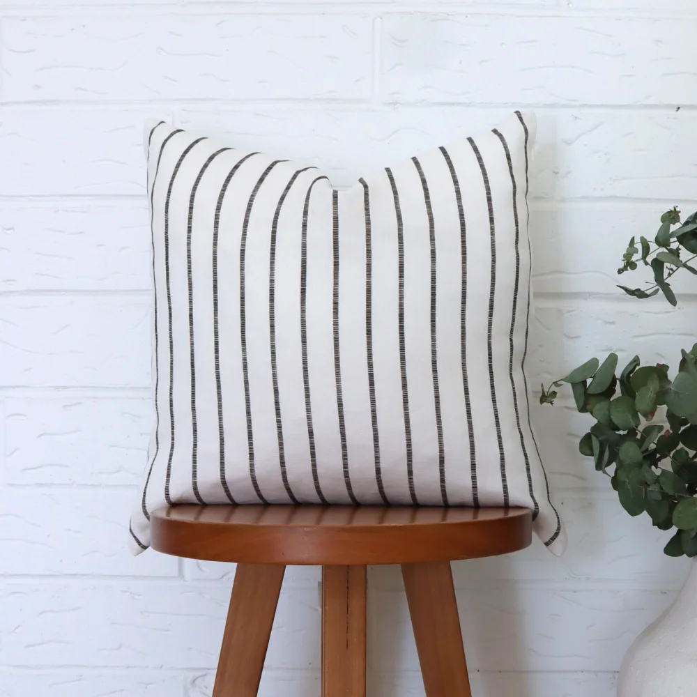 A black and white cushion positioned on a dark wood stool.