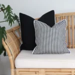 Two black and white cushions arranged on light coloured seating outside.