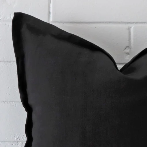 Close range image of black linen cushion. The square size and linen material can be seen in detail.