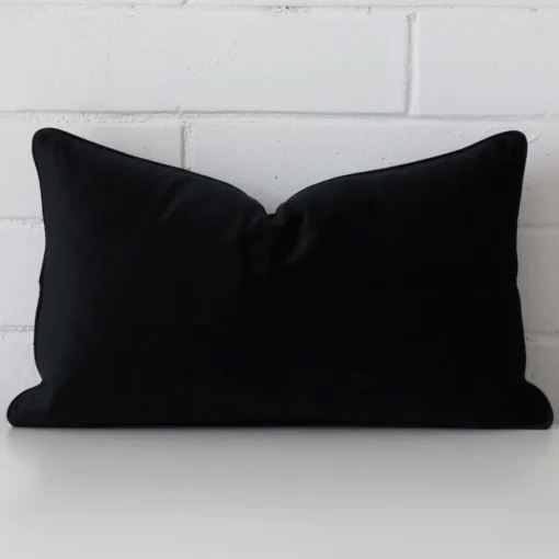 Black velvet cushion cover features prominently against a white wall. It is a rectangle design.