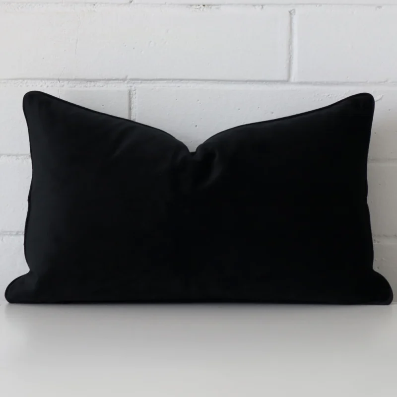 black-velvet-rectangular-cushion-cover-30cm-x-50cm-sc764-30 Black velvet cushion cover features prominently against a white wall. It is a rectangle design.