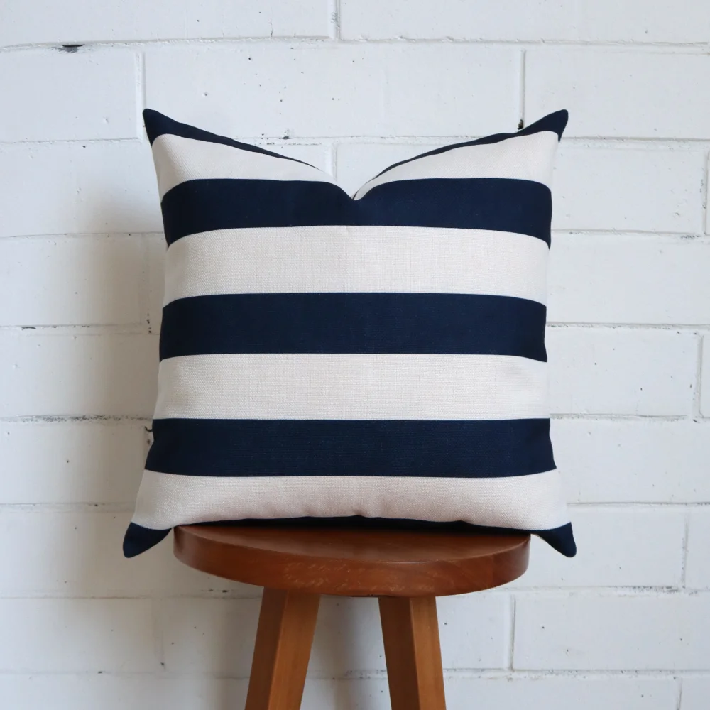 A blue and white cushion stands vertically on a wooden stool.