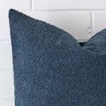 The corner of this boucle square cushion cover is shown close up. The blue colour is shown in greater detail.