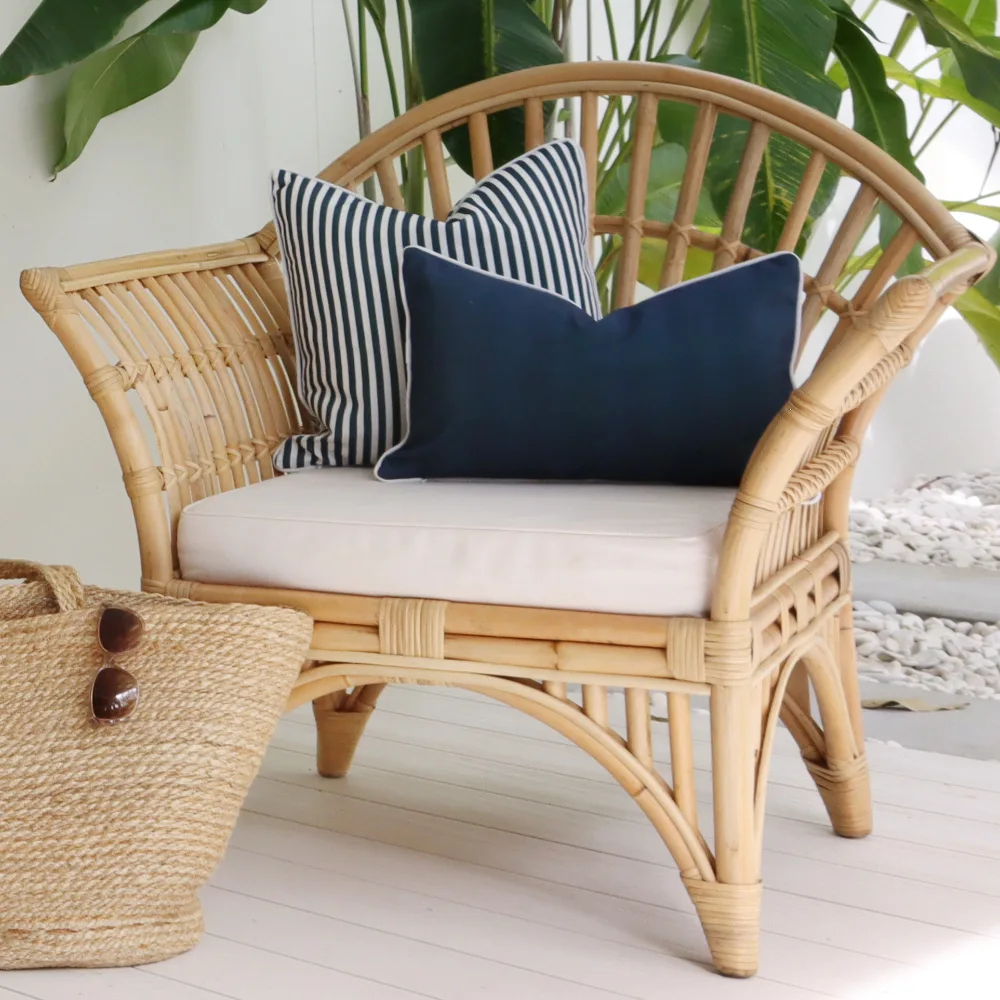 Two blue outdoor cushions are sitting on a rattan seat outside.