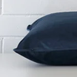 A sideways perspective of this velvet cushion. The positioning shows the border of the square shape and the blue colour.