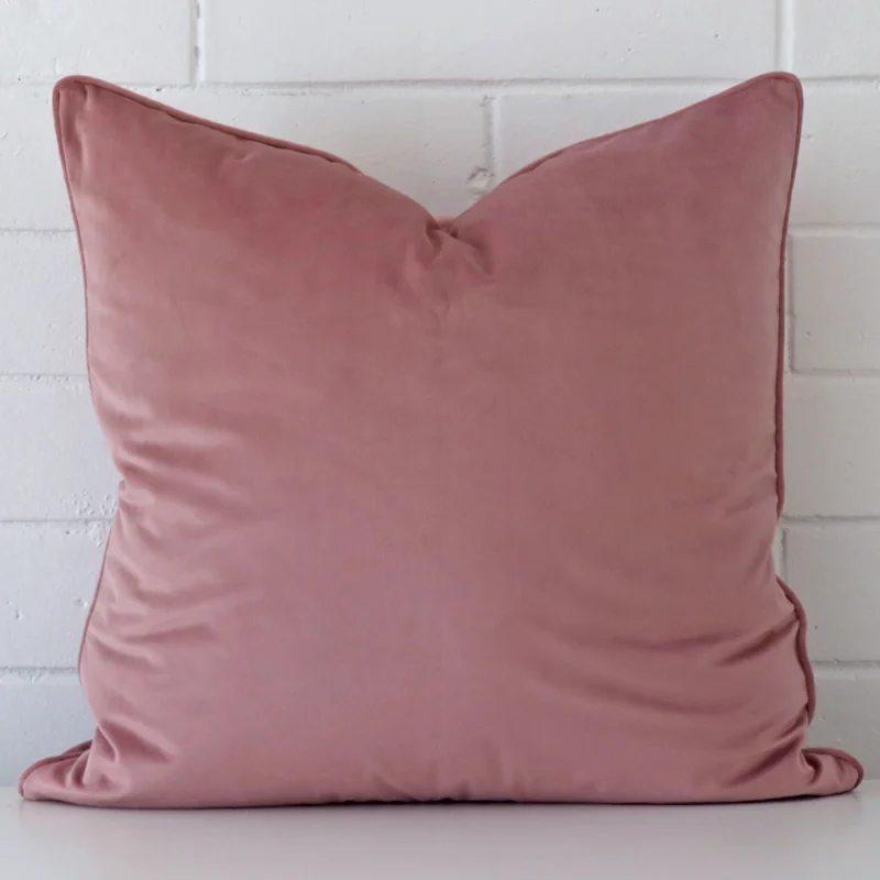 blush-velvet-cushion-cover-55cm-x-55cm-sc777-55b White wall with blush cushion laying against it. It has distinctive velvet fabric and has a square shape.