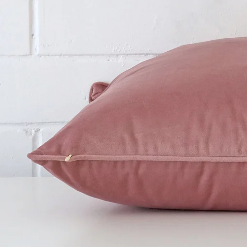 Square cushion cover in blush colour sitting flat. The sideways viewpoint shows the seams of the velvet material.