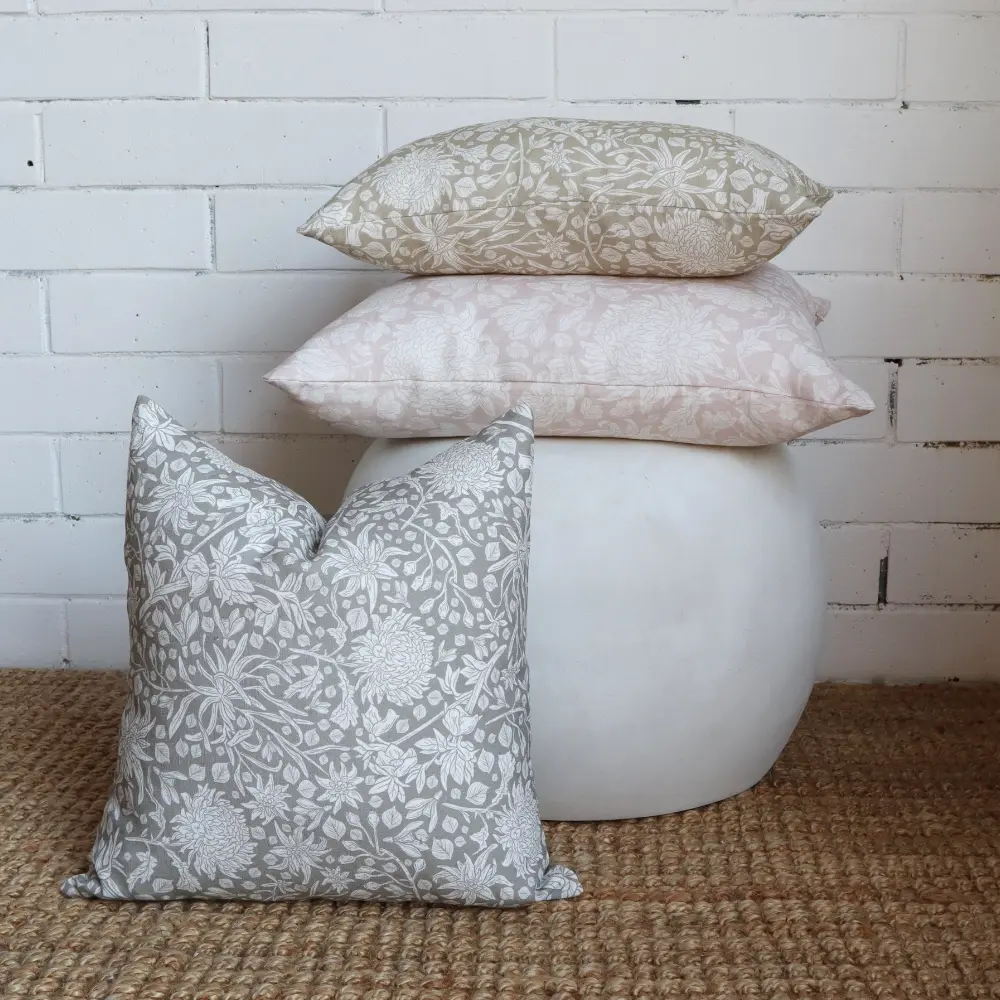 Three boho cushions are stacked on the floor in front of a low side table.