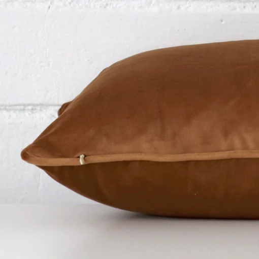 Bronze cushion cover laid on its back side. The image shows a side-on view of the velvet material and its rectangle dimensions.