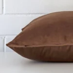brown cushion cover laid on its back side. The image shows a side-on view of the velvet material and its square dimensions.