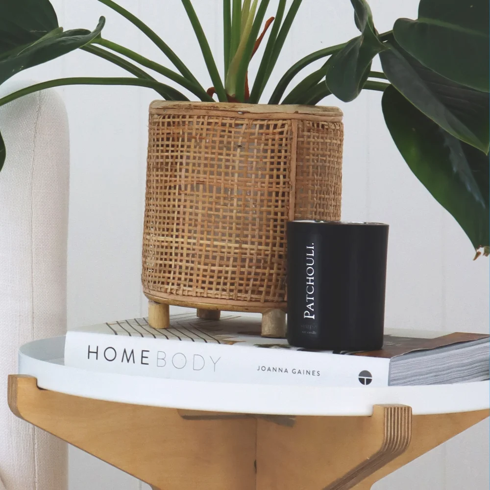 A candle is standing on a side table with a book.