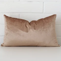 Bold rectangle champagne cushion positioned in front of white brickwork. The velvet fabric is comfortably soft.