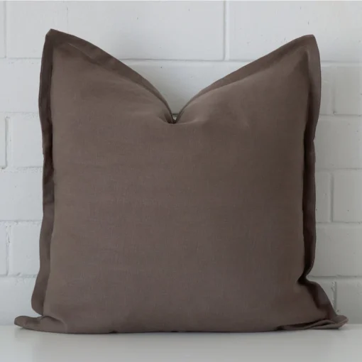 Chocolate Brown linen cushion cover features prominently against a white wall. It is a square design.