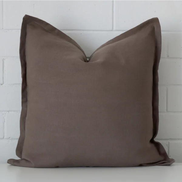 Chocolate Brown linen cushion cover features prominently against a white wall. It is a square design.
