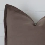 Cropped shot of top left corner of this chocolate brown cushion cover. This viewpoint shows the linen fabric and square shape with more precision.