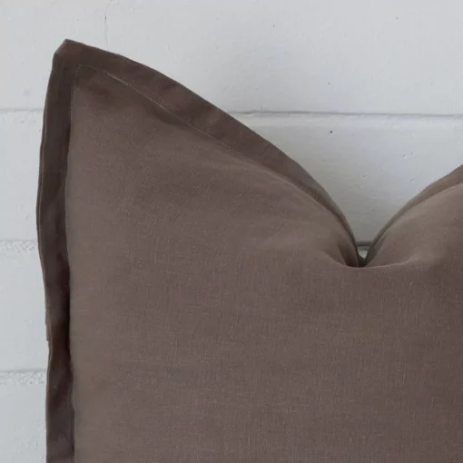 Cropped shot of top left corner of this chocolate brown cushion cover. This viewpoint shows the linen fabric and square shape with more precision.