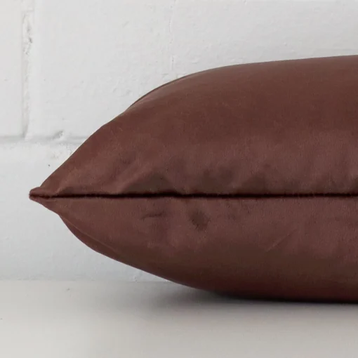 Chocolate brown cushion cover laid on its back side. The image shows a side-on view of the velvet material and its square dimensions.