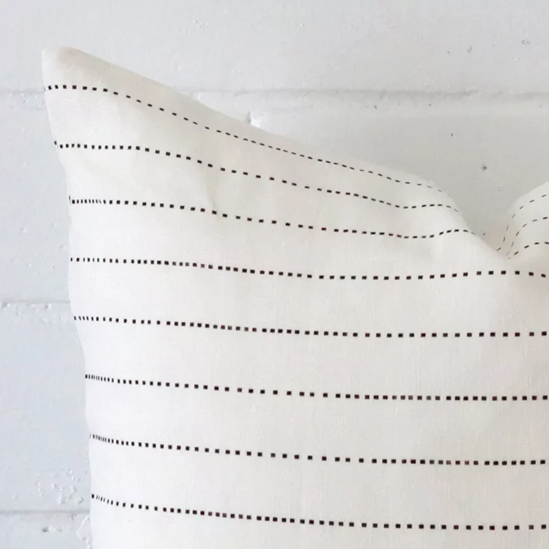 Square striped cushion sitting upright in front of a brick wall. It has been made from a quality linen material.