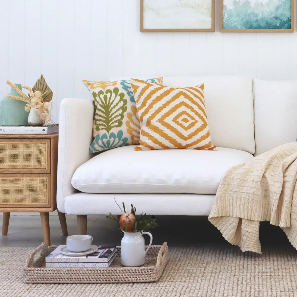 Two coastal cushions styled on a seat in a beach themed room.