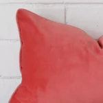 A detailed shot of this coral cushion cover that has velvet fabric and a rectangle size.
