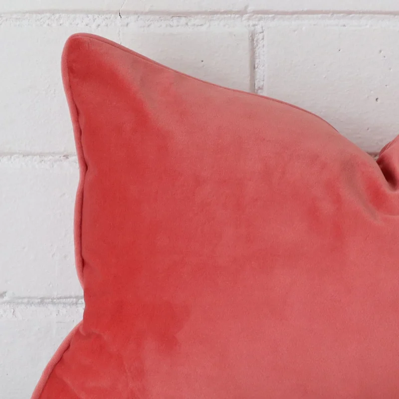 A detailed shot of this coral cushion cover that has velvet fabric and a rectangle size.