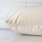 A side view of cream cushion that has velvet fabric and a rectangle size.