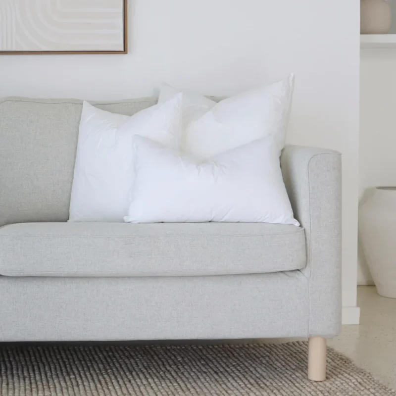 cushion-insert-faux-feather-couch-set-of-3b A set of 3 indoor faux feather cushion inserts positioned on the end of a couch.