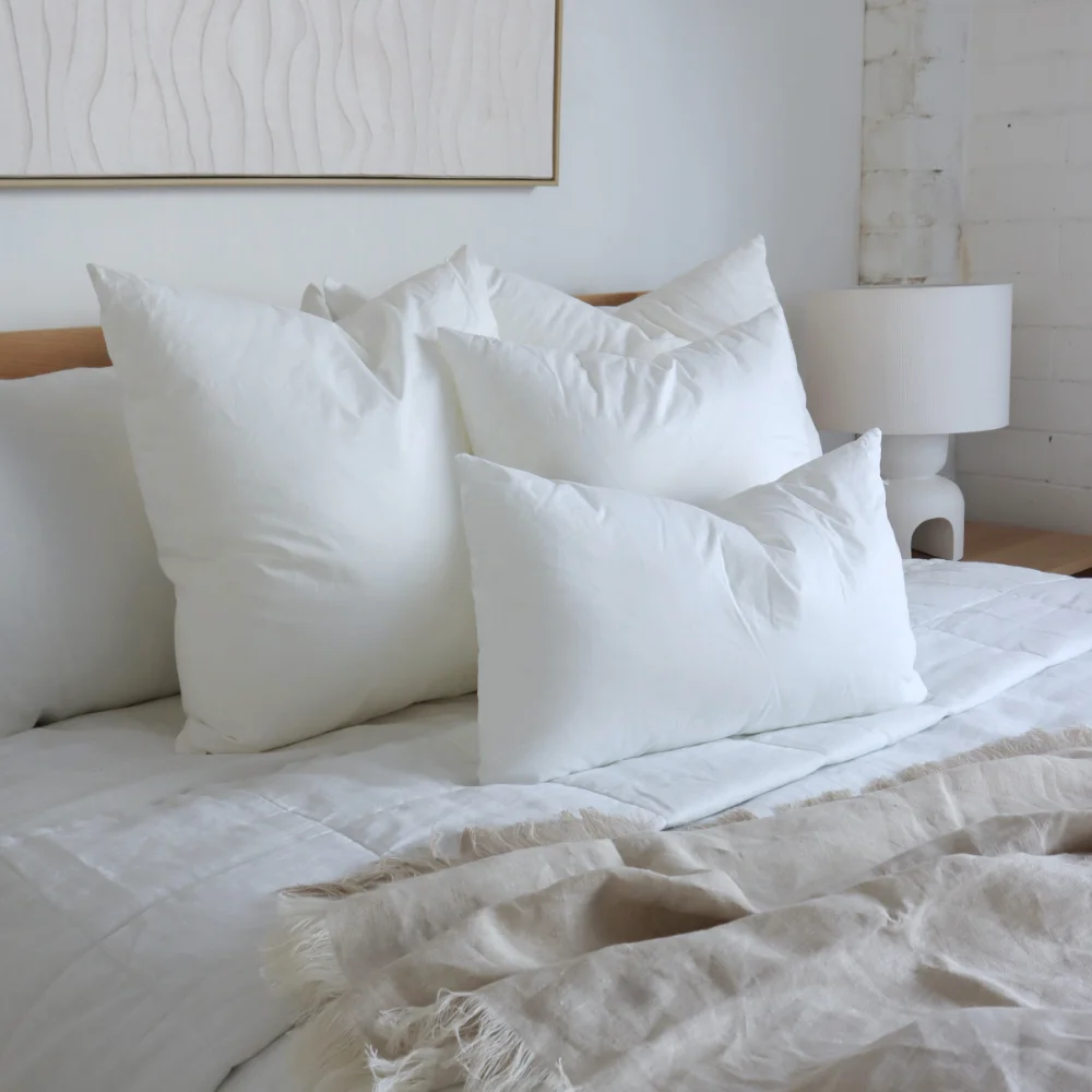 Four cushion inserts in different sizes are arranged on a bed.