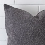 A macro image of the top left corner of this boucle cushion. It is possible to see the finer detail of the square shape and dark grey colour.